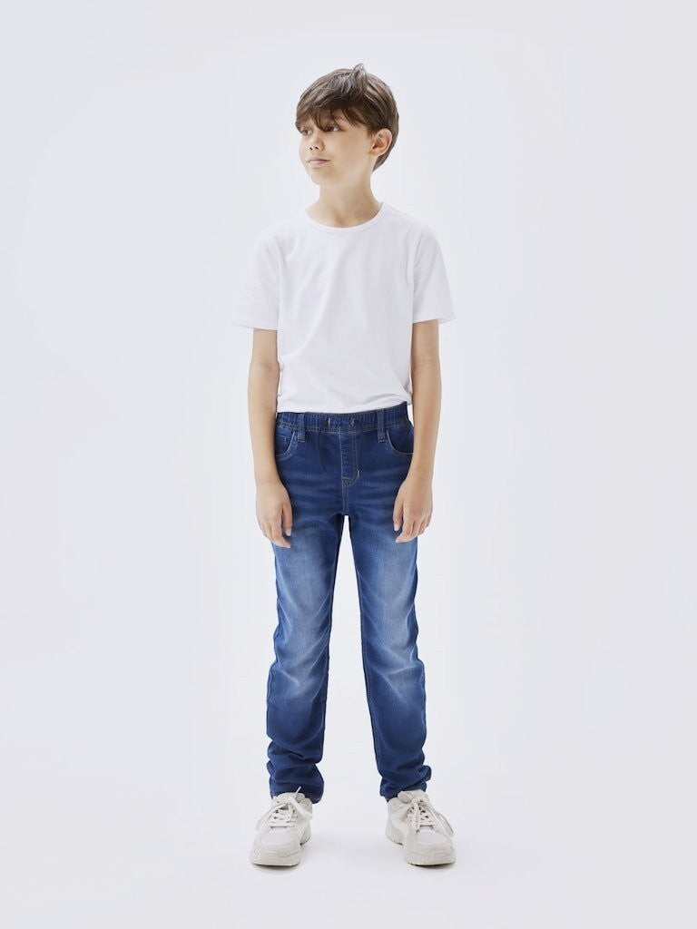 Bambino indossa jeans Scugnizzi 0-16 in denim blu con vita elasticizzata e coulisse, abbinati a t-shirt bianca