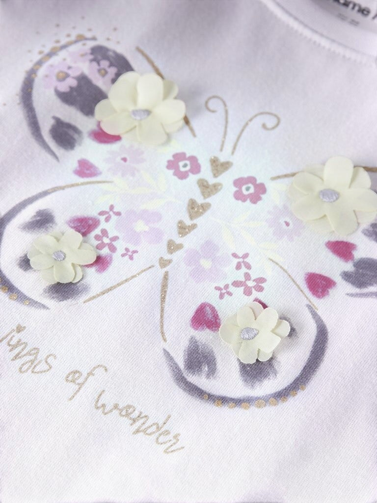 Dettaglio maglietta Scugnizzi 0-16 Name It con farfalla, applicazioni floreali in rilievo, glitter e scritta Wings of wonder