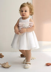 Abito da cerimonia bianco Scugnizzi con fiocco floreale in tulle rosa cipria, silhouette a trapezio, ideale per bambine.