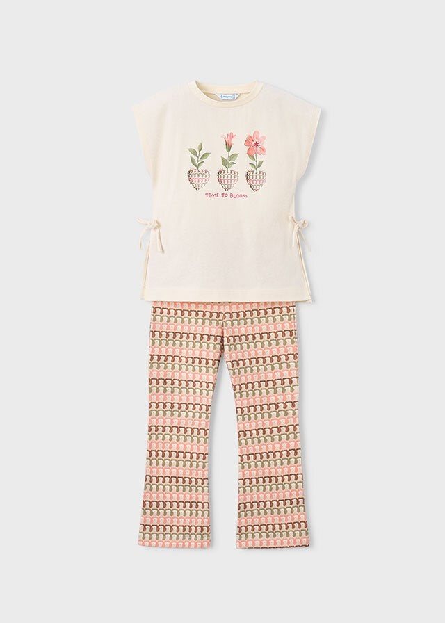 Set Scugnizzi 0-16: T-shirt color crema con stampa floreale "Time to Bloom" e laccetti laterali, abbinata a pantaloni con stampa geometrica rosa e marrone.