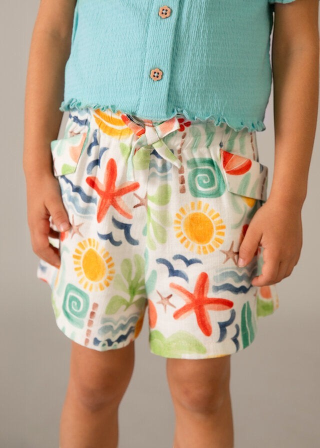 Scugnizzi 0-16 shorts da bambina con stampa tropicale di soli, stelle marine e onde. Vita elasticizzata con laccetto e tasche.