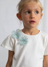 T-shirt bianca in cotone per bambina Scugnizzi 0-16 con applicazioni floreali azzurre in tulle e strass, maniche corte a sbuffo.
