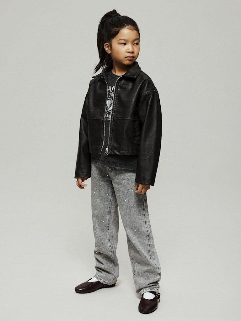Bambina indossa pantaloni Scugnizzi 0-16 in denim a gamba larga, lavaggio chiaro con strass e giacca nera in ecopelle