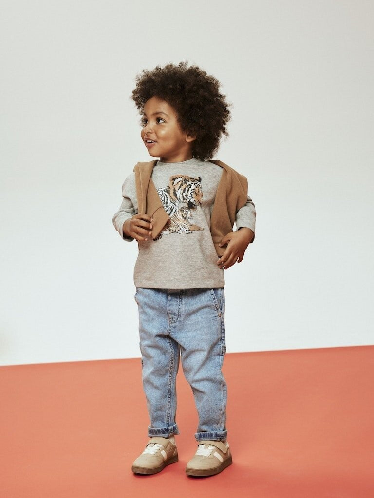 Bambino indossa jeans Name It Scugnizzi 0-16 in denim chiaro con vita elasticizzata e maglia grigia con tigre