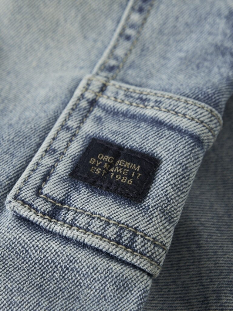 Dettaglio etichetta in tessuto su jeans cargo in denim lavaggio chiaro del brand Scugnizzi 0-16 per bambini