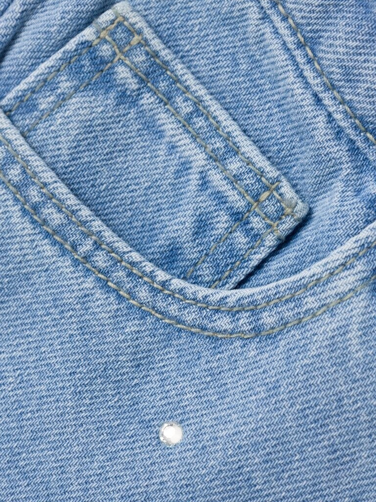 Dettaglio di jeans Scugnizzi 0-16 in denim azzurro chiaro con cuciture a contrasto e applicazione di strass luminosi.
