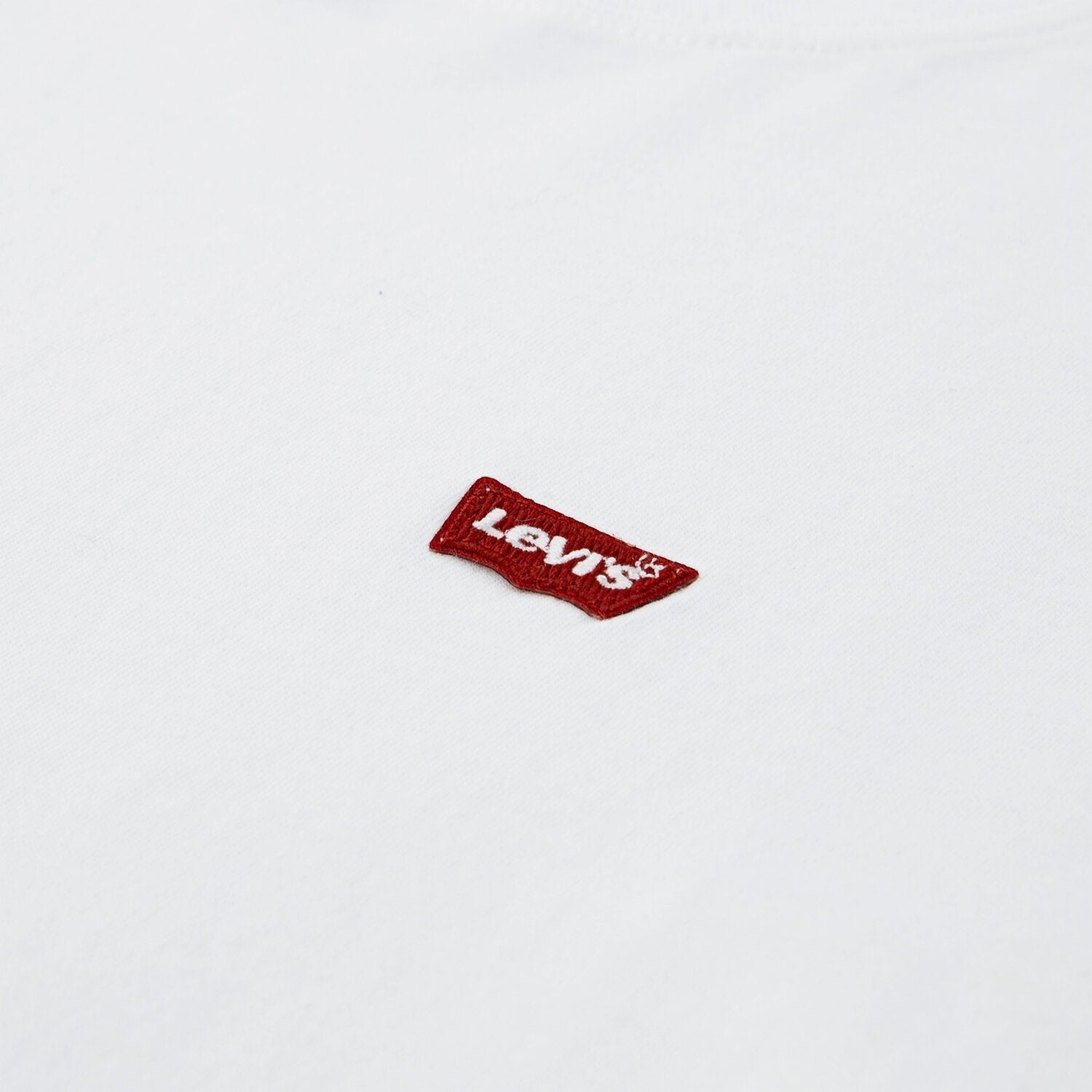Dettaglio del logo Levi's rosso ricamato su una maglietta bianca in cotone di Scugnizzi 0-16