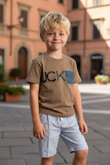 Bambino biondo indossa una t-shirt marrone Scugnizzi 0-16 con stampa grafica e taschino in denim in una piazza