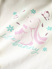 Dettaglio stampa grafica Scugnizzi 0-16 su maglietta in cotone color crema con coniglietto, fiori e farfalle