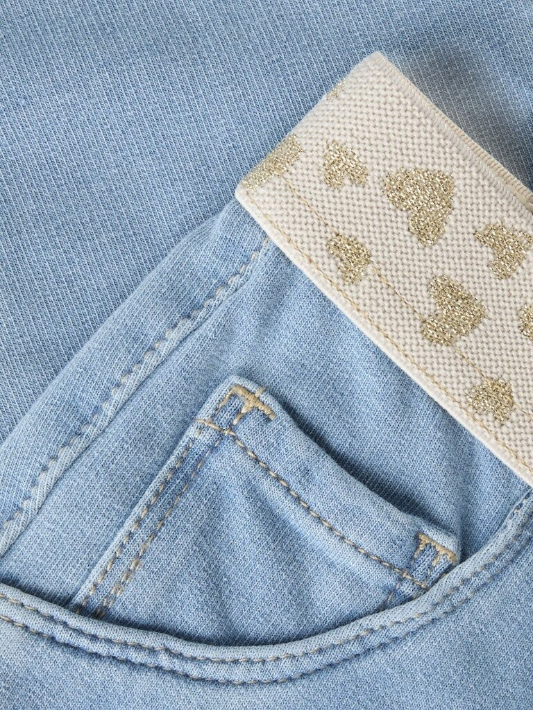 Dettaglio di pantaloni in denim Scugnizzi 0-16 lavaggio chiaro con vita elastica crema e cuoricini glitterati dorati