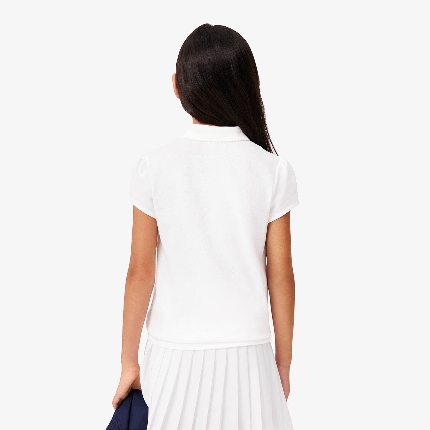 Vista posteriore di una bambina che indossa una polo bianca Lacoste in piqué di cotone con maniche arricciate