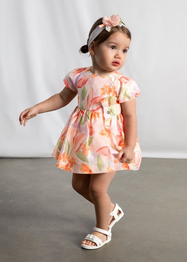 Abito estivo Scugnizzi 0-16 per bambina con stampa floreale arancione, rosa e lilla, maniche a sbuffo e fiocco decorativo.