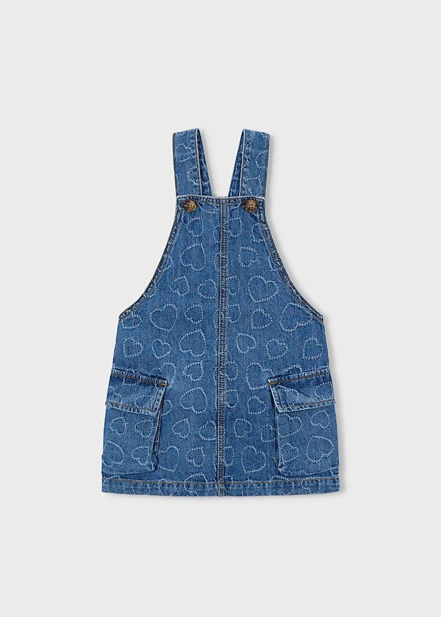 Abito salopette in denim blu per bambina Scugnizzi 0-16 con motivo a cuori all-over, tasche applicate e spalline regolabili.